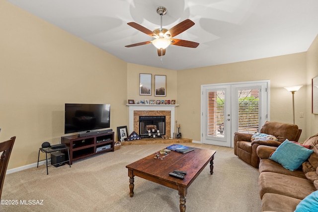 carpeted living room featuring baseboards, a ceiling fan, a fireplace, and french doors