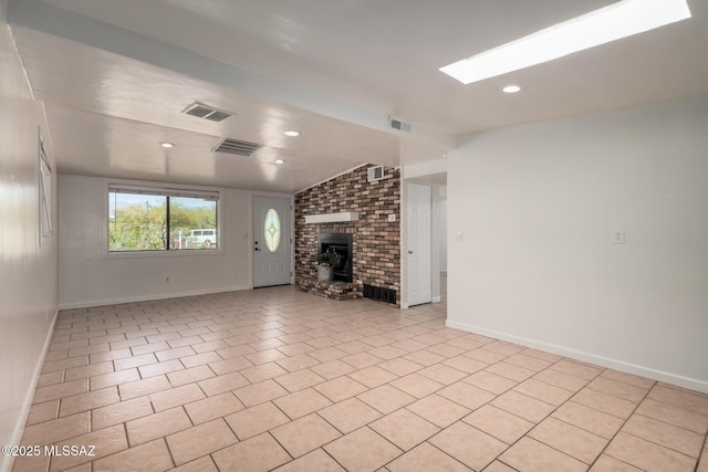 5914 E Beverly St, Tucson, AZ 85711 - unfurnished living room featuring baseboards, vaulted ceiling with skylight, a fireplace, and visible vents