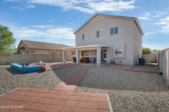 back of house featuring an outdoor fire pit, stucco siding, a fenced backyard, central air condition unit, and a patio