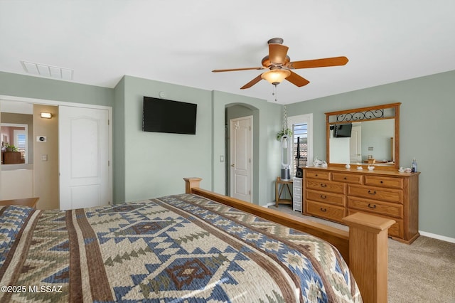 bedroom with light carpet, arched walkways, a ceiling fan, baseboards, and visible vents