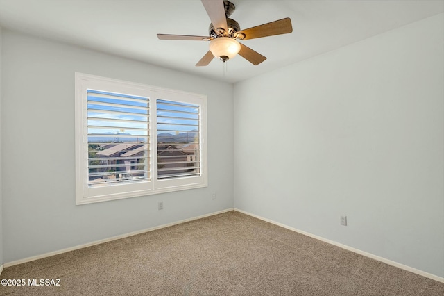 unfurnished room with a ceiling fan, baseboards, and carpet