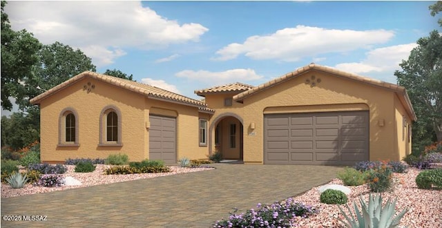 mediterranean / spanish-style home featuring stucco siding, an attached garage, and decorative driveway
