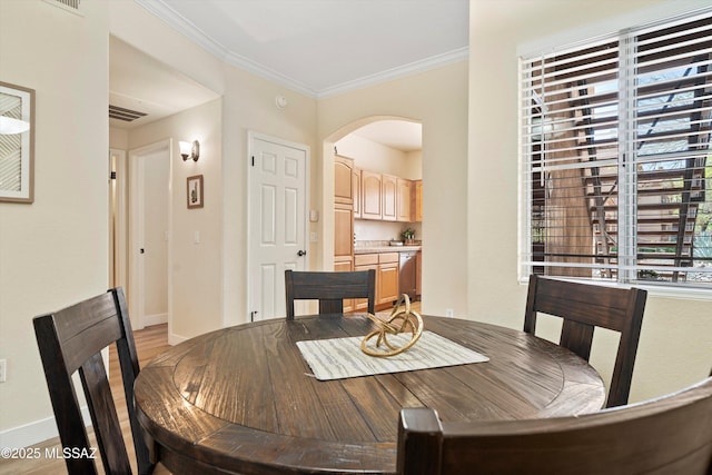 7050 E Sunrise Dr Unit 1104, Tucson, AZ 85750 - dining space featuring arched walkways, baseboards, light wood-style floors, and ornamental molding