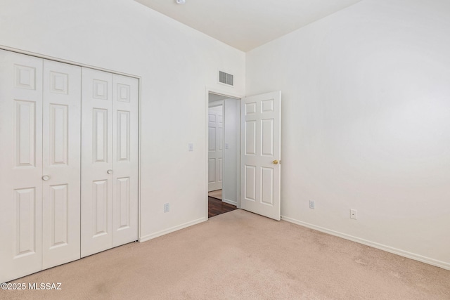 unfurnished bedroom with baseboards, carpet flooring, visible vents, and a closet