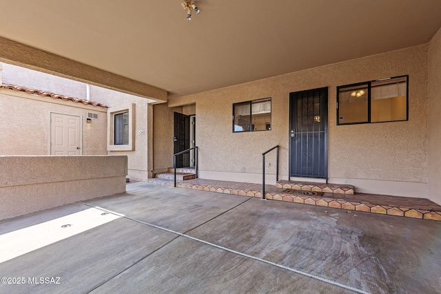 property entrance with stucco siding and a patio area