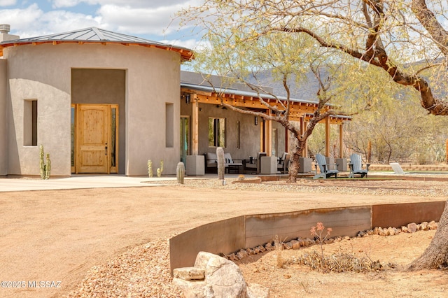 back of property featuring a standing seam roof, a patio area, metal roof, and stucco siding