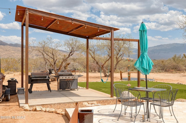 view of patio / terrace with outdoor dining area, a grill, and a mountain view