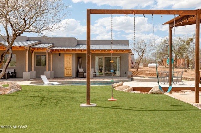 back of house with a standing seam roof, stucco siding, a patio area, metal roof, and an outdoor pool