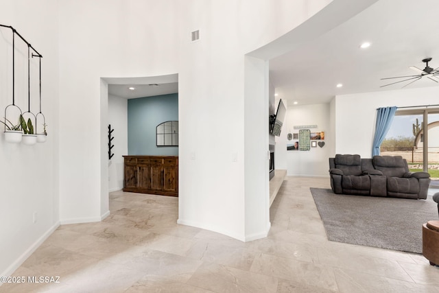 living area featuring a fireplace, visible vents, baseboards, and ceiling fan
