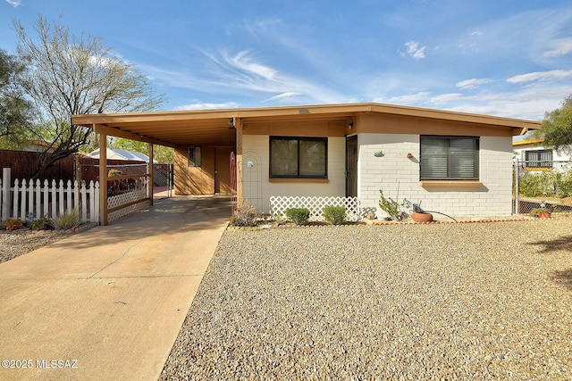 view of front of home with brick siding, fence, concrete driveway, and a carport