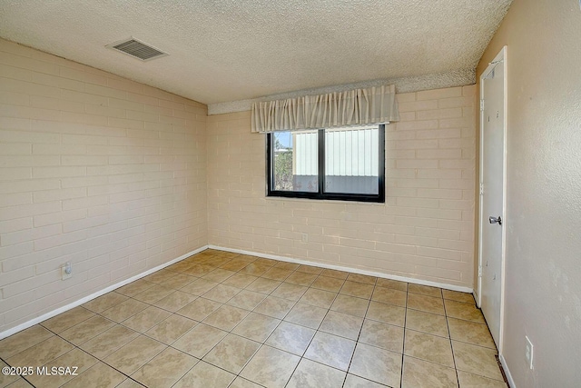 empty room featuring a textured ceiling, brick wall, and visible vents