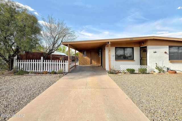 view of front of property with an attached carport, fence, brick siding, and concrete driveway