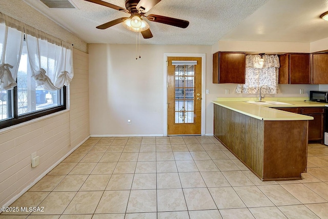 kitchen featuring light countertops, a sink, light tile patterned flooring, visible vents, and black microwave