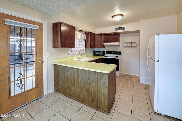 kitchen featuring visible vents, under cabinet range hood, a sink, electric range oven, and freestanding refrigerator
