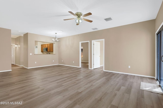 unfurnished living room with ceiling fan with notable chandelier, visible vents, baseboards, and light wood-type flooring
