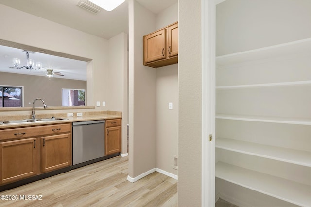 kitchen featuring a sink, a chandelier, light wood finished floors, dishwasher, and visible vents