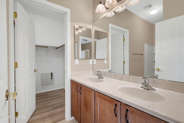 full bath with visible vents, a sink, double vanity, and wood finished floors