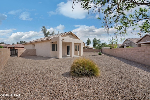 rear view of property featuring a patio, stucco siding, a gate, and fence private yard