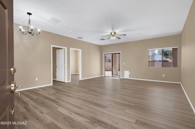 empty room with ceiling fan with notable chandelier, visible vents, light wood-style flooring, and baseboards