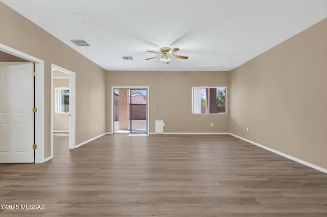 empty room with baseboards, ceiling fan, visible vents, and light wood-type flooring