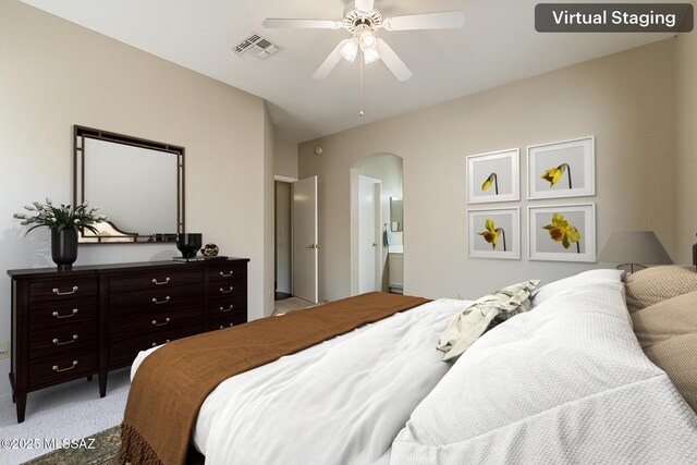 2525 N Camino Reloj, Green Valley, AZ 85614 - bedroom featuring arched walkways, light carpet, ceiling fan, and ensuite bath
