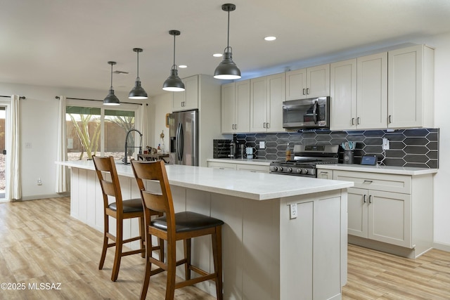 2301 W Montrose Pl, Tucson, AZ 85741 - kitchen with light countertops, appliances with stainless steel finishes, a kitchen island with sink, and tasteful backsplash
