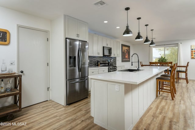 2301 W Montrose Pl, Tucson, AZ 85741 - kitchen featuring appliances with stainless steel finishes, a sink, light wood finished floors, backsplash, and visible vents