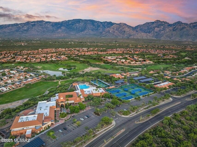aerial view at dusk with a water and mountain view, golf course view, and a residential view
