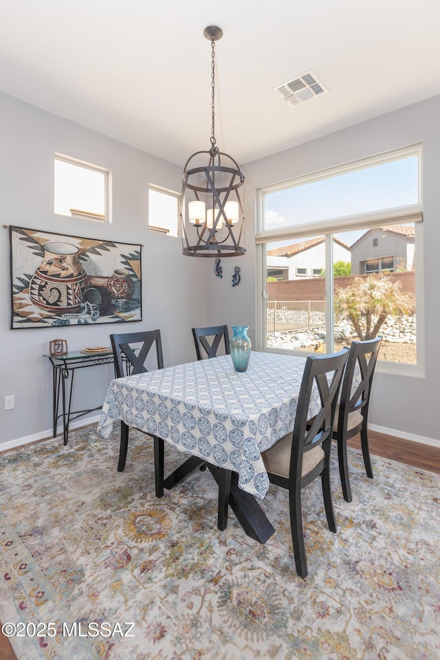 dining area with baseboards, an inviting chandelier, visible vents, and wood finished floors