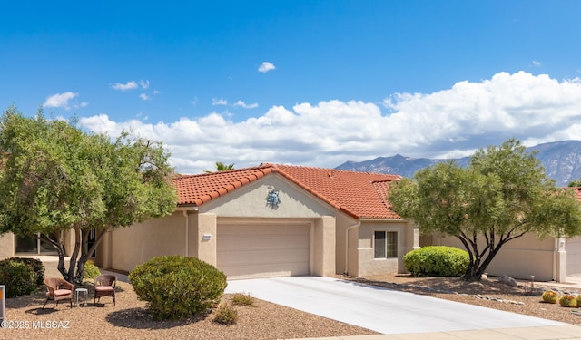 mediterranean / spanish-style house featuring an attached garage, a mountain view, a tiled roof, stucco siding, and driveway
