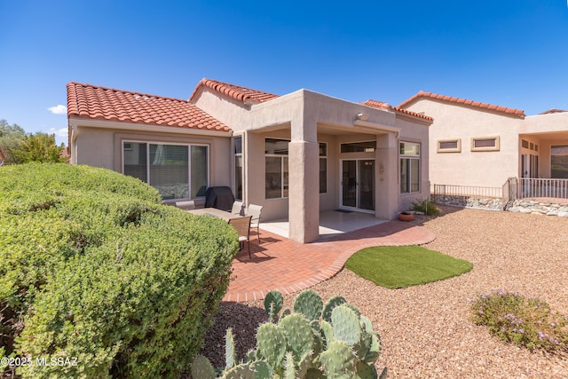 rear view of house with a tiled roof, a patio, stucco siding, and fence