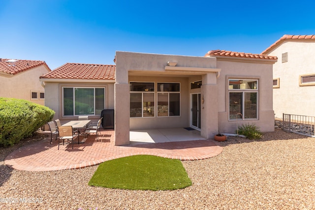 rear view of house with a patio, stucco siding, and a tiled roof