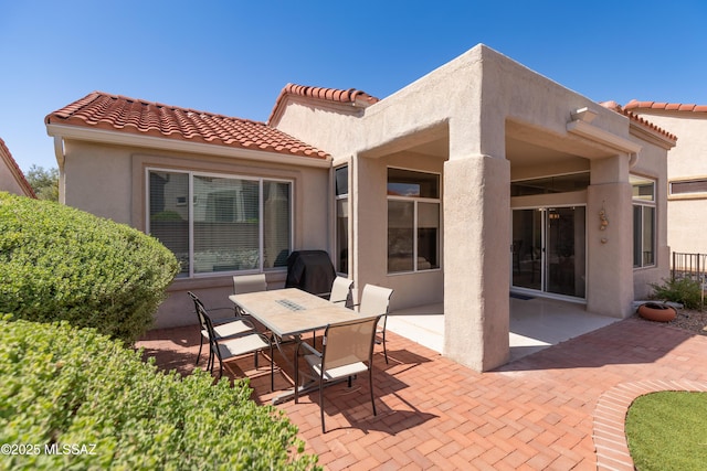 rear view of house featuring a patio area, stucco siding, and a tile roof