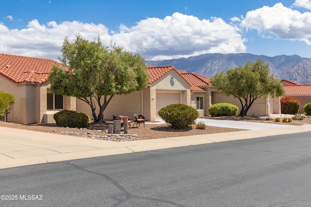 mediterranean / spanish home featuring a tiled roof, a mountain view, an attached garage, stucco siding, and concrete driveway
