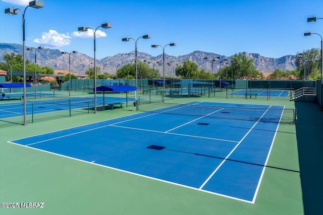 view of tennis court featuring fence and a mountain view