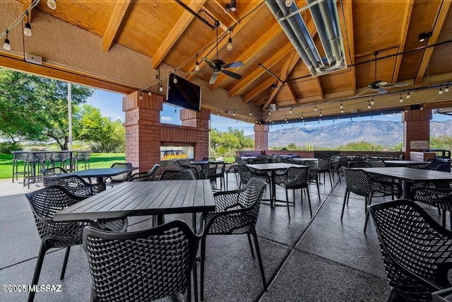view of patio with a gazebo, an outdoor brick fireplace, outdoor dining space, and a ceiling fan