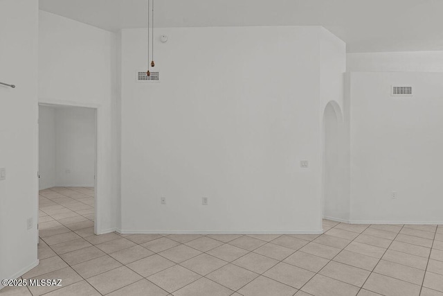 spare room with light tile patterned flooring, visible vents, and arched walkways