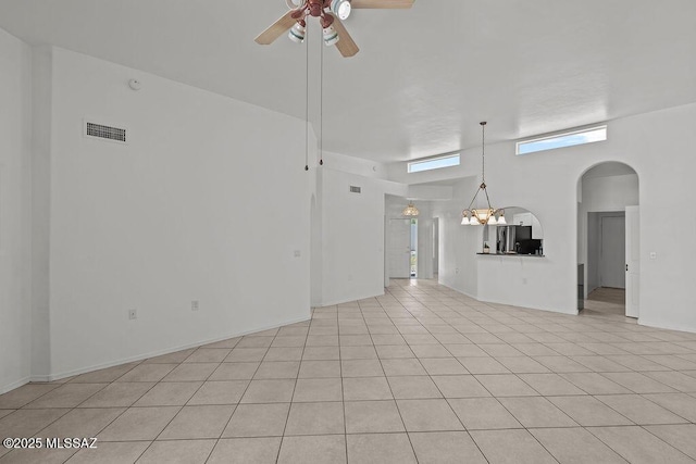 unfurnished living room featuring light tile patterned floors, arched walkways, visible vents, and ceiling fan