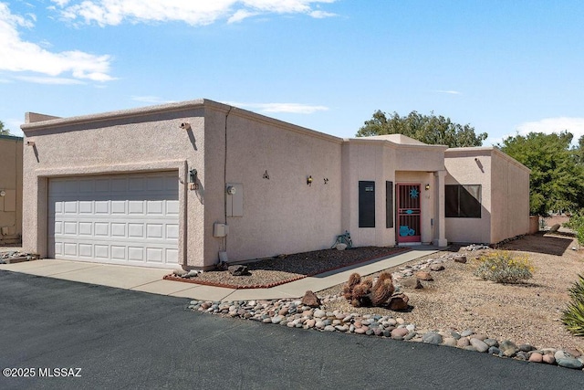 adobe home with a garage, stucco siding, and aphalt driveway