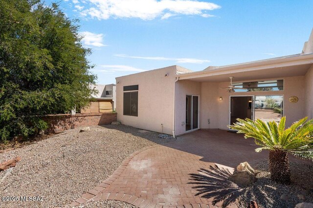 rear view of house featuring stucco siding, a ceiling fan, and a patio area