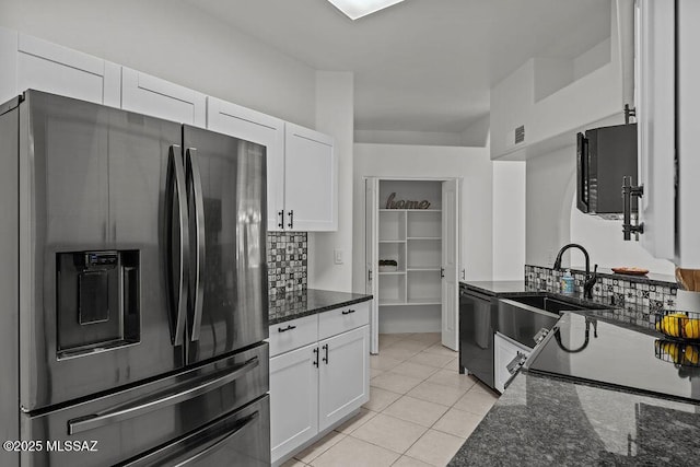 kitchen with dark stone countertops, light tile patterned floors, white cabinetry, tasteful backsplash, and black appliances