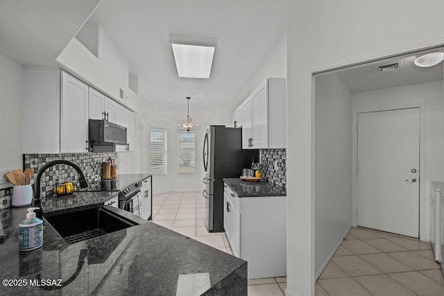 kitchen featuring white cabinets, light tile patterned floors, decorative backsplash, and a sink