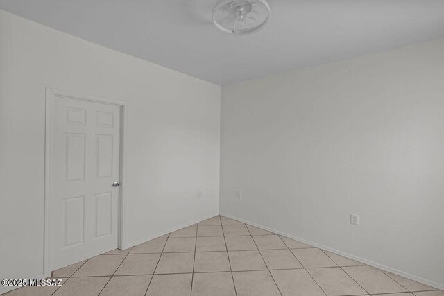 spare room with baseboards and light tile patterned floors