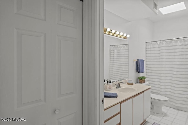 full bath featuring tile patterned flooring, vanity, toilet, visible vents, and a skylight