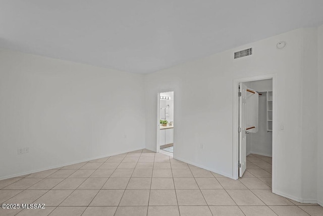 empty room featuring light tile patterned floors, visible vents, and baseboards