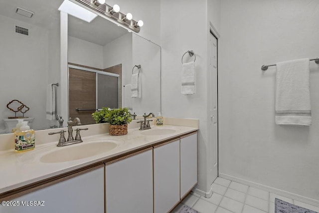 bathroom featuring double vanity, a sink, a shower stall, and visible vents