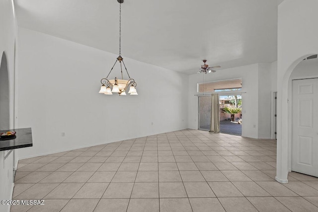 spare room featuring light tile patterned floors, arched walkways, and ceiling fan with notable chandelier