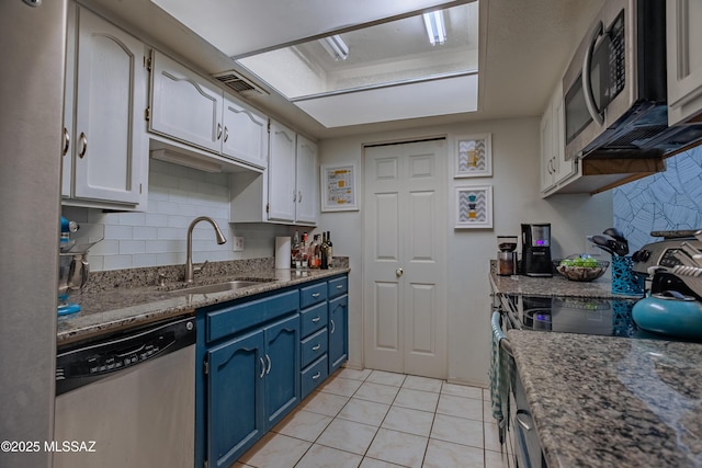 kitchen featuring white cabinets, blue cabinetry, appliances with stainless steel finishes, a sink, and light tile patterned floors