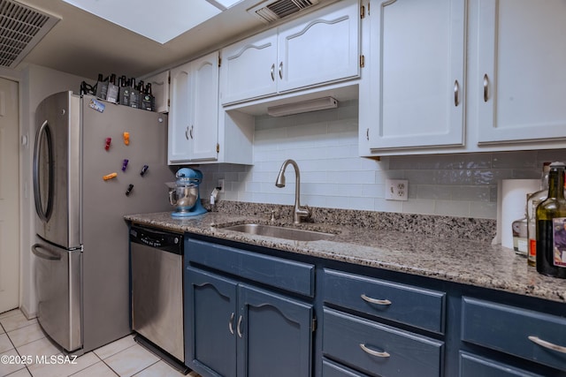 kitchen featuring light tile patterned floors, stainless steel appliances, blue cabinets, a sink, and visible vents
