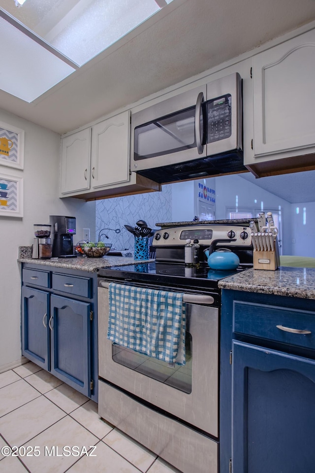 kitchen featuring blue cabinetry, appliances with stainless steel finishes, white cabinetry, backsplash, and light tile patterned floors